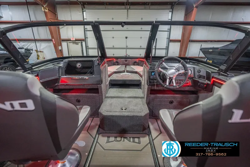 Slide: The Image of 2026 Lund 1875 Crossover XS boat interior in showroom with seating and console view. - 17