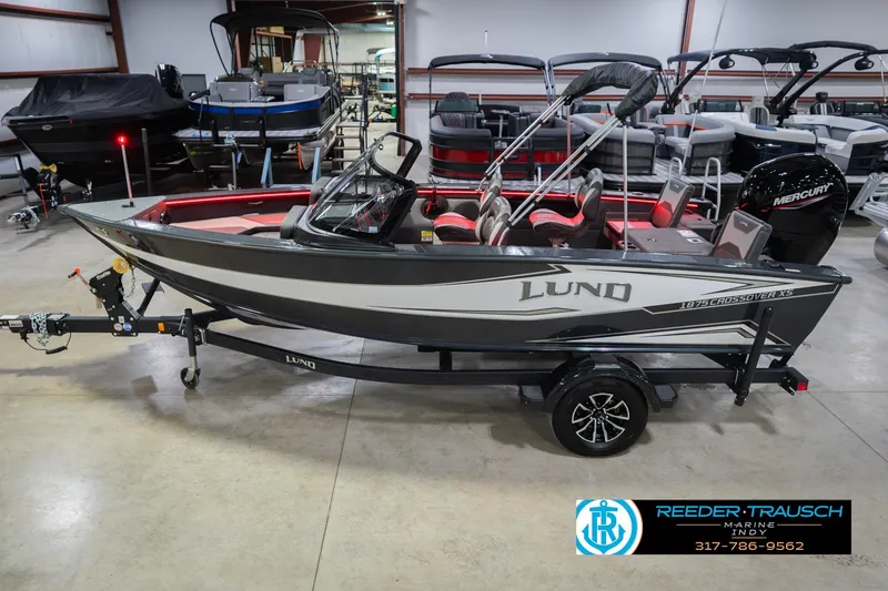Slide: The Image of 2026 Lund 1875 Crossover XS boat in showroom, black and white design, on trailer. - 2