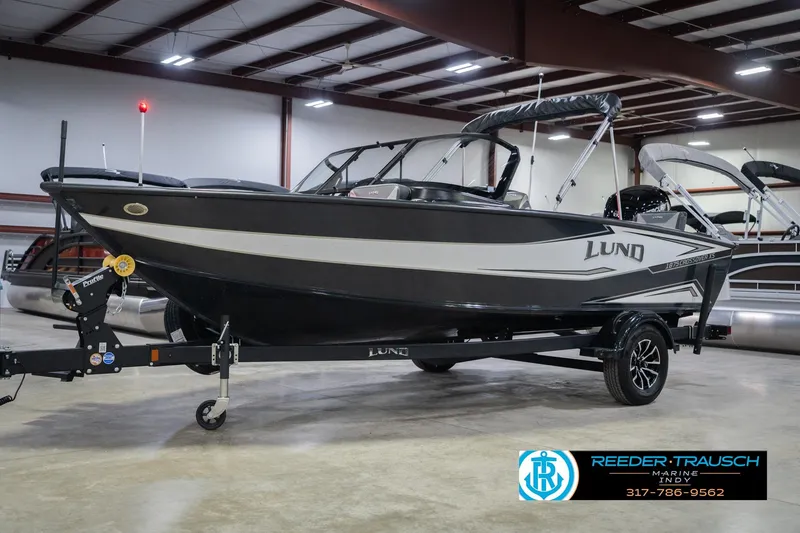 Slide: The Image of 2026 Lund 1875 Crossover XS boat in showroom, front view, with trailer. - 3