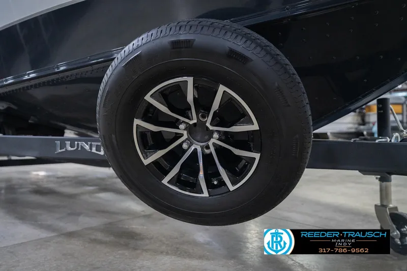 Slide: The Image of 2026 Lund 1875 Crossover XS trailer wheel, black alloy rim, Reeder-Trausch Marine logo. - 62