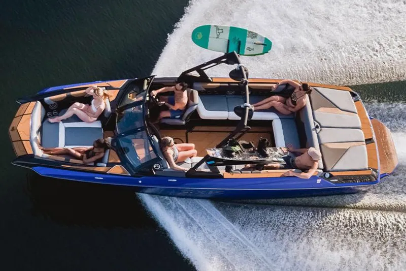 Slide: The Image of 2023 Axis A24 boat parked outside dealership with vehicles and trees in background. - 5