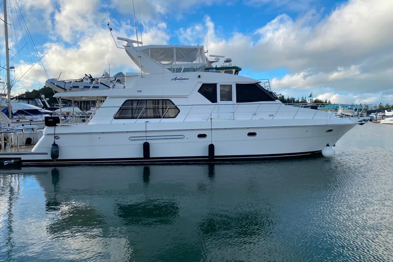 The Image of White 2001 Compass 57 yacht docked in marina under blue sky. - 0