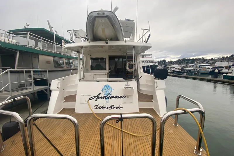 Slide: The Image of Compass 57 yacht docked at marina, showcasing rear deck and boat name. - 3