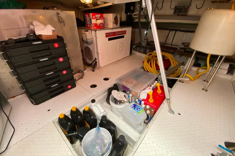 Slide: The Image of Engine room of 2001 Compass 57 yacht with tools, oil containers, and storage boxes. - 59