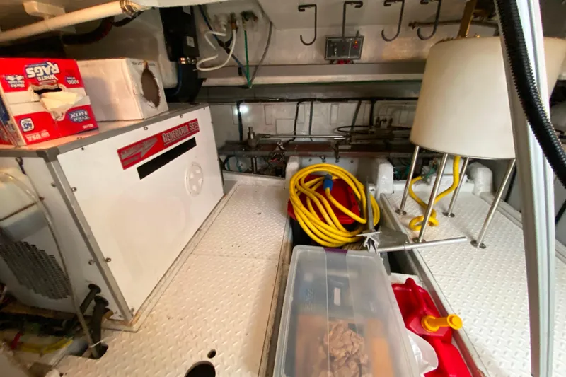 Slide: The Image of Engine room of 2001 Compass 57 yacht with generator, hoses, and storage. - 62