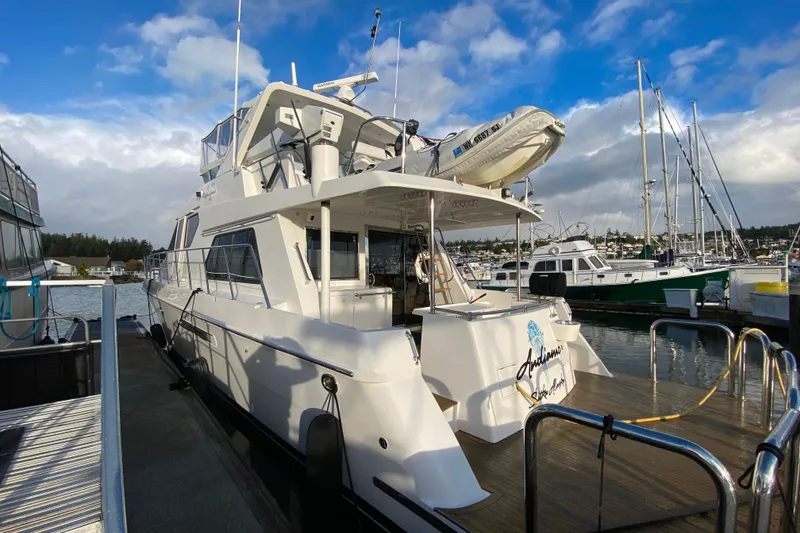 Slide: The Image of Luxurious 2001 Compass 57 yacht docked at a marina under a partly cloudy sky. - 74