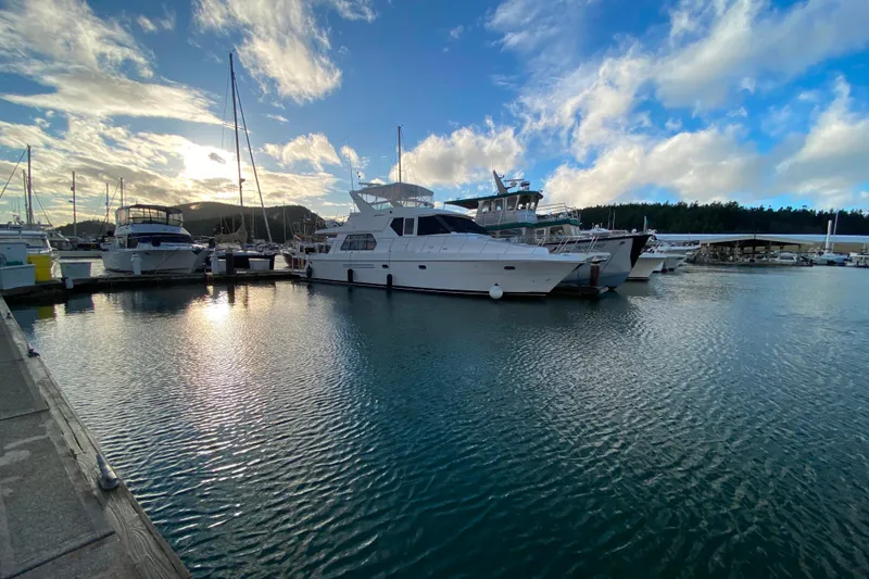 Slide: The Image of Boats docked at marina under cloudy sky, featuring a 2001 Compass 57 yacht. - 77