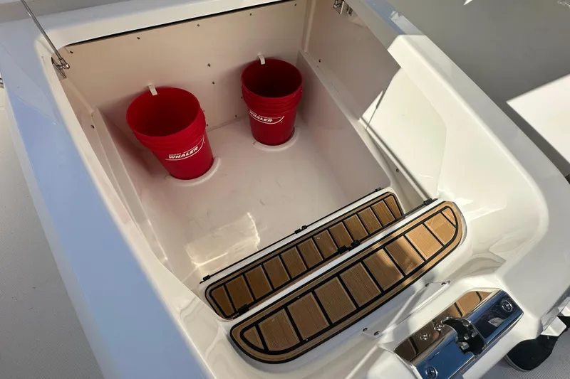 Slide: The Image of Boston Whaler 280 Outrage 2026 with red buckets in storage compartment. - 14