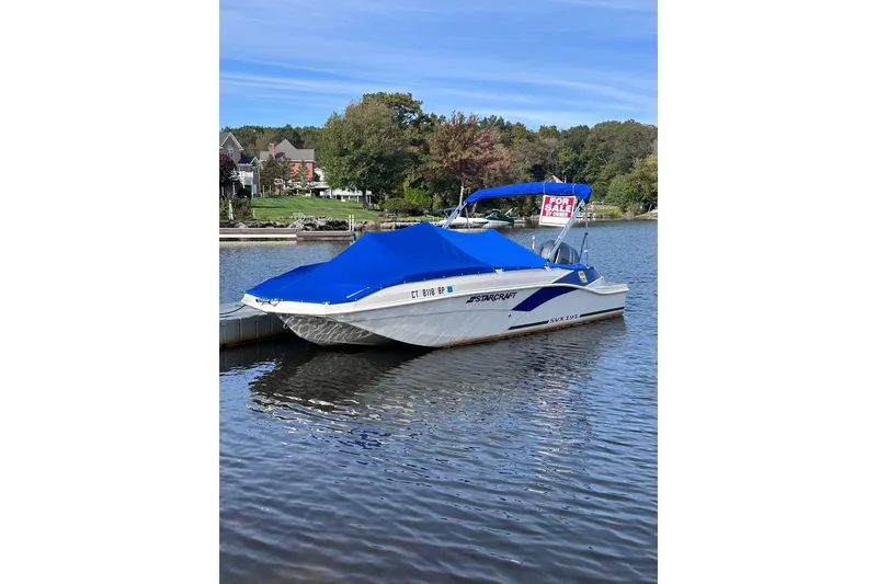 Slide: The Image of 2023 Starcraft SVX 191 OB boat with blue cover, docked, for sale sign visible. - 3