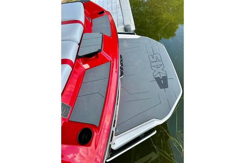 Slide: The Image of Red 2021 Axis A20 boat with gray swim platform, docked on calm water. - 10