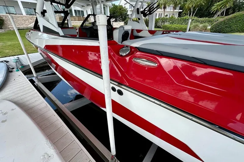 Slide: The Image of Red and white 2021 Axis A20 boat docked on a lift near a waterfront property. - 12