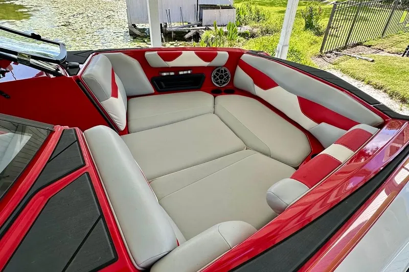 Slide: The Image of 2021 Axis A20 boat interior with red and white seating, near a lakeside dock. - 22