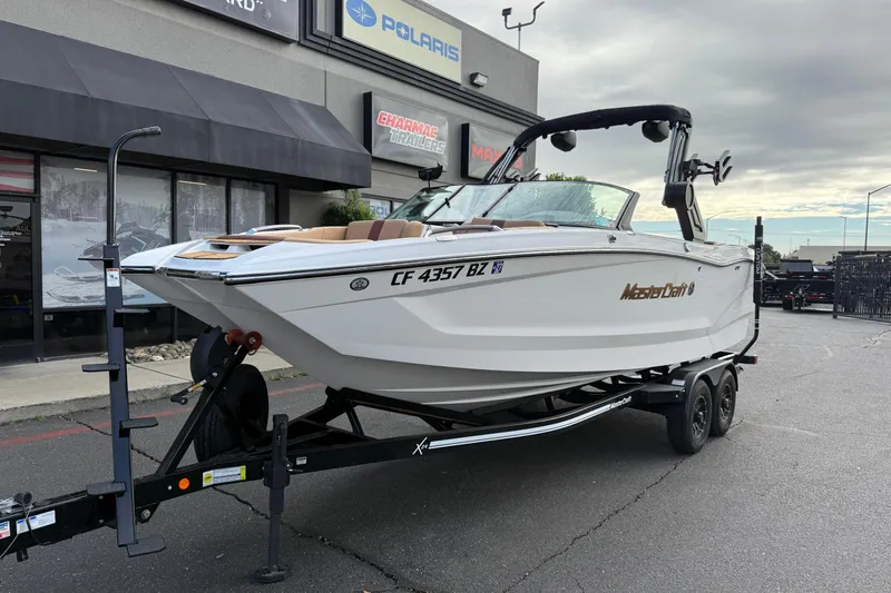 Slide: The Image of 2025 MasterCraft X24 boat on trailer, parked outside dealership. - 20