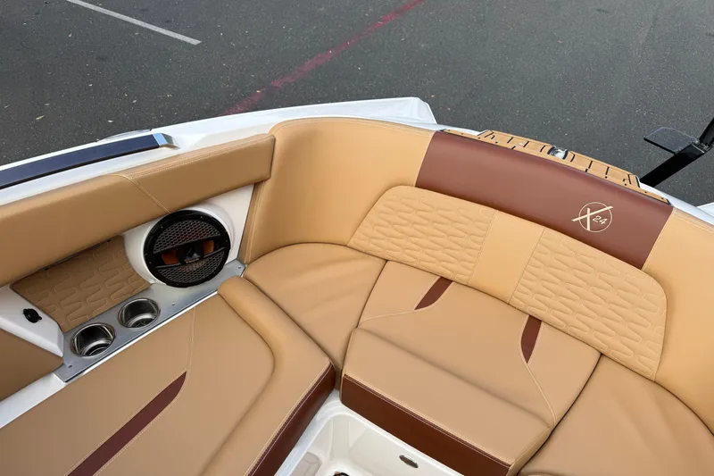 Slide: The Image of 2025 MasterCraft X24 boat interior with tan and brown leather seating, featuring cup holders and speaker. - 42