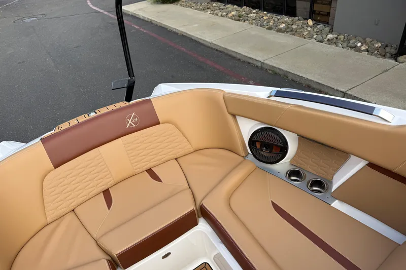 Slide: The Image of 2025 MasterCraft X24 boat interior with tan and brown seating, speaker, and cup holders. - 44