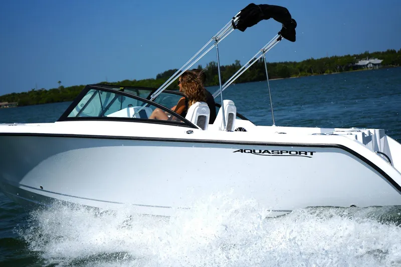 Slide: The Image of 2025 Aquasport 22AS Dual Console boat cruising on open water. - 2