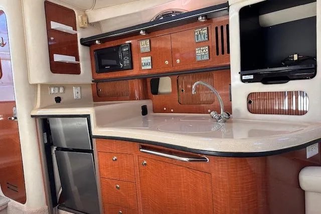 Slide: The Image of Interior of 2002 Sea Ray 340 Sundancer yacht with kitchenette, featuring wood cabinetry and appliances. - 36
