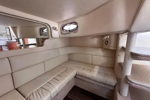 Slide: The Image of 2002 Sea Ray 340 Sundancer cabin interior with beige leather seating and porthole windows. - 54