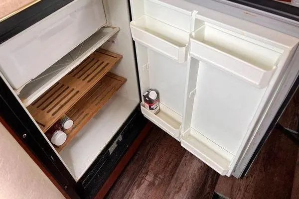 Slide: The Image of Open refrigerator inside a 2002 Sea Ray 340 Sundancer boat, showing shelves and door storage. - 65