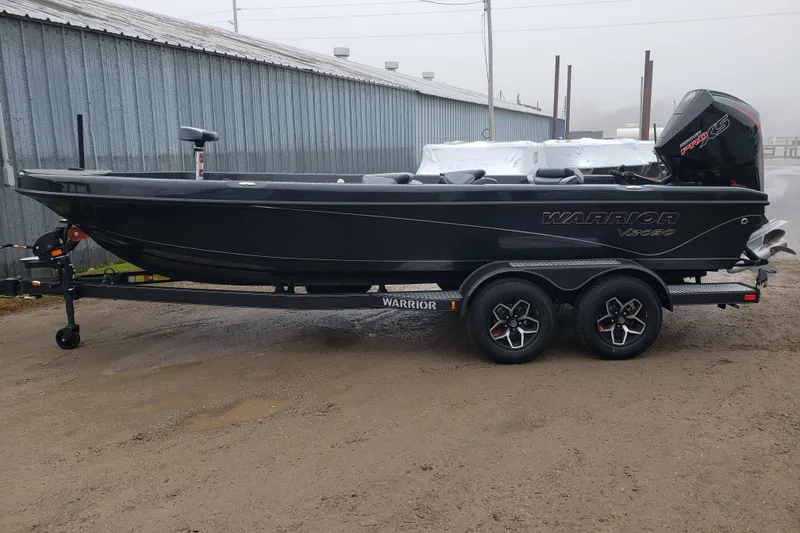 Slide: The Image of 2026 Warrior V2090 boat on trailer, parked outdoors near a metal building. - 2