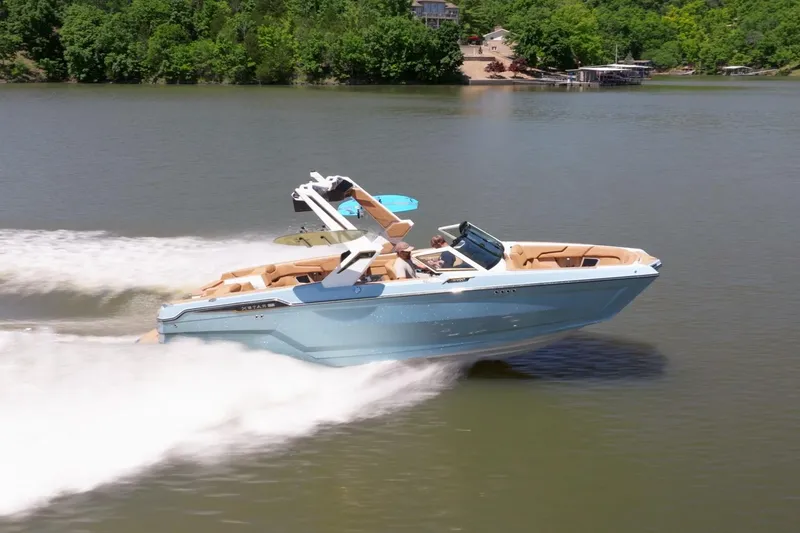 The Image of 2025 MasterCraft XStar 25 speedboat cruising on a lake with lush green surroundings. - 1