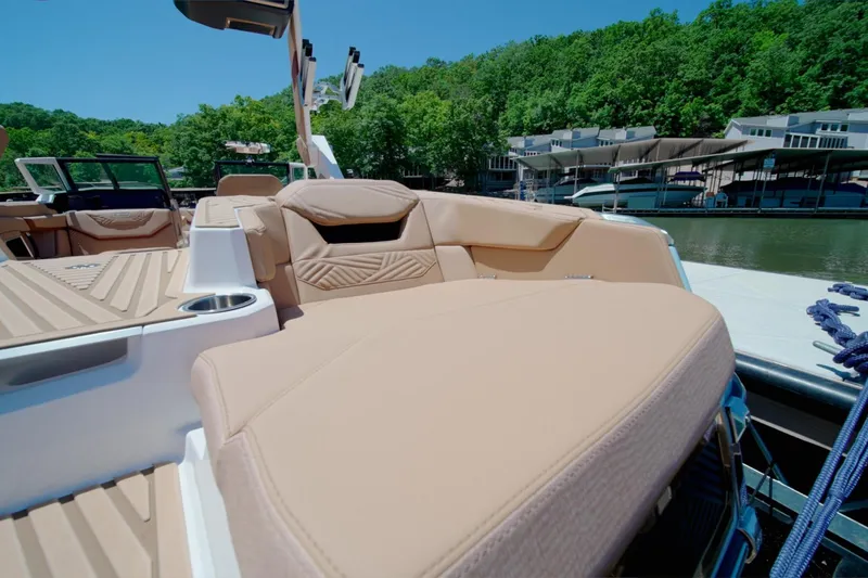 Slide: The Image of 2025 MasterCraft XStar 25 boat with luxurious seating, docked by a scenic waterfront. - 22