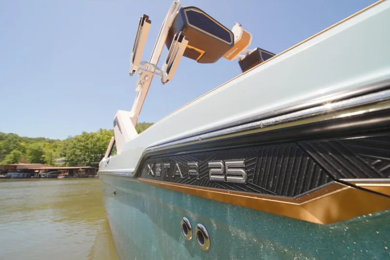 Slide: The Image of 2025 MasterCraft XStar 25 boat on a sunny lake, showcasing sleek design. - 3