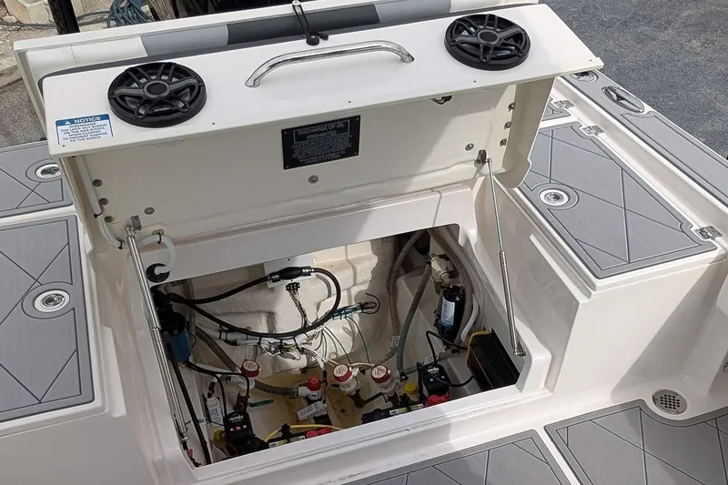 Slide: The Image of 2023 Robalo 266 Cayman boat storage compartment with open hatch and visible wiring. - 10
