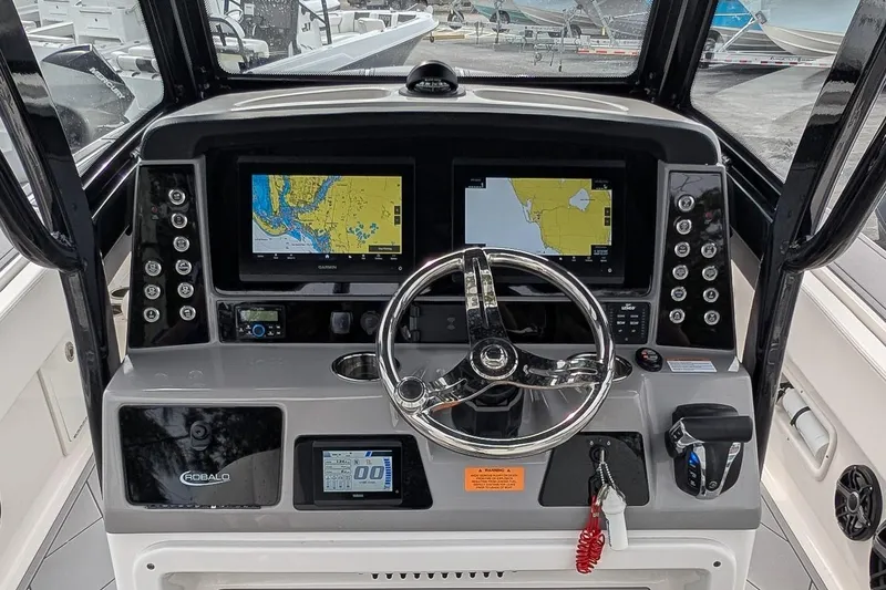 Slide: The Image of 2023 Robalo 266 Cayman boat dashboard with dual navigation screens and steering wheel. - 13
