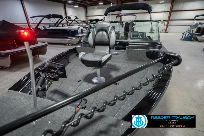 Slide: The Image of 2026 Lund 2075 Impact XS boat interior in showroom with seating and equipment. - 12