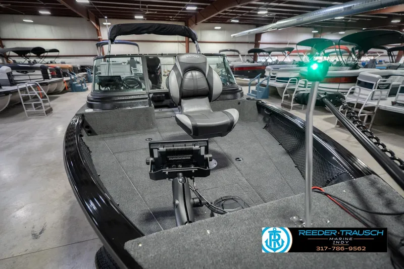 Slide: The Image of 2026 Lund 2075 Impact XS boat in showroom, featuring seating and navigation equipment. - 13