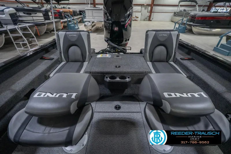 Slide: The Image of 2026 Lund 2075 Impact XS boat interior with seating and storage in a showroom. - 22
