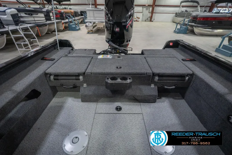 Slide: The Image of 2026 Lund 2075 Impact XS boat interior with storage compartments and motor in showroom. - 24