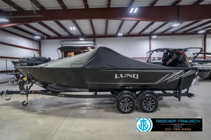 Slide: The Image of 2026 Lund 2075 Impact XS boat with cover in a showroom, on a trailer. - 64