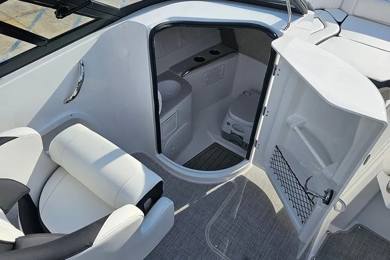 Slide: The Image of 2026 Stingray 211 DC boat interior with open door revealing compact restroom. - 21