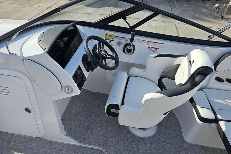 Slide: The Image of 2026 Stingray 211 DC boat cockpit with steering wheel and white captain's chair. - 22