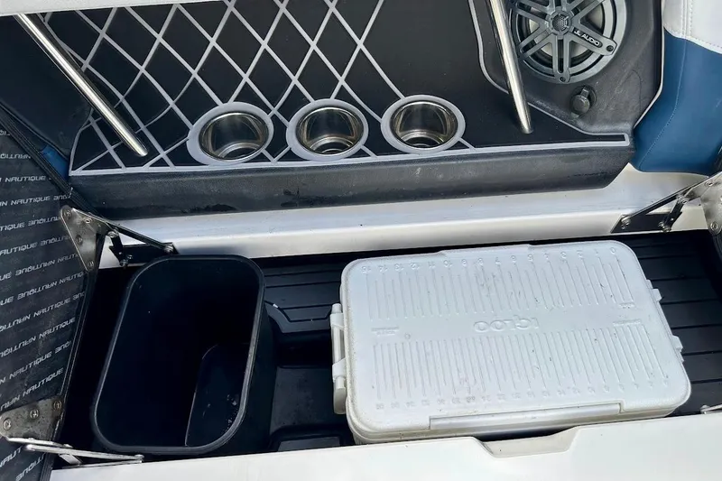 Slide: The Image of 2018 Correct Craft Super Air Nautique GS22 storage area with cooler, cup holders, and speaker. - 24