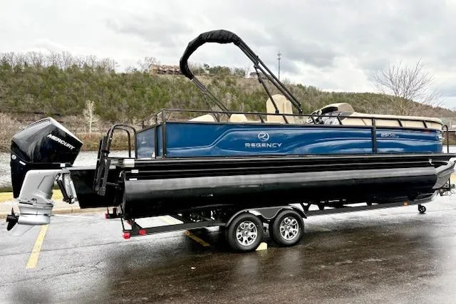 Slide: The Image of 2025 Regency 250 DL3 pontoon boat on trailer, parked outdoors. - 2