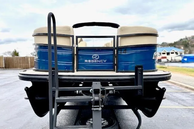 Slide: The Image of 2025 Regency 250 DL3 pontoon boat on trailer, rear view, blue and beige design. - 6