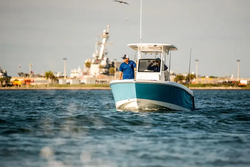 The Image of 2026 Edgewater 230CC boat cruising on water near industrial shoreline. - 1