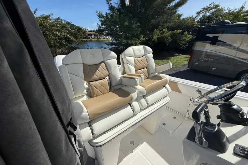 Slide: The Image of 2021 Edgewater 262CC boat interior with luxurious seating and steering wheel, near a scenic lake. - 12