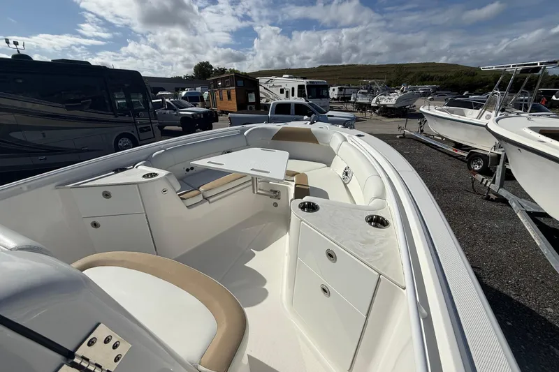 Slide: The Image of 2021 Edgewater 262CC boat interior with seating and table, parked among other boats and RVs. - 16