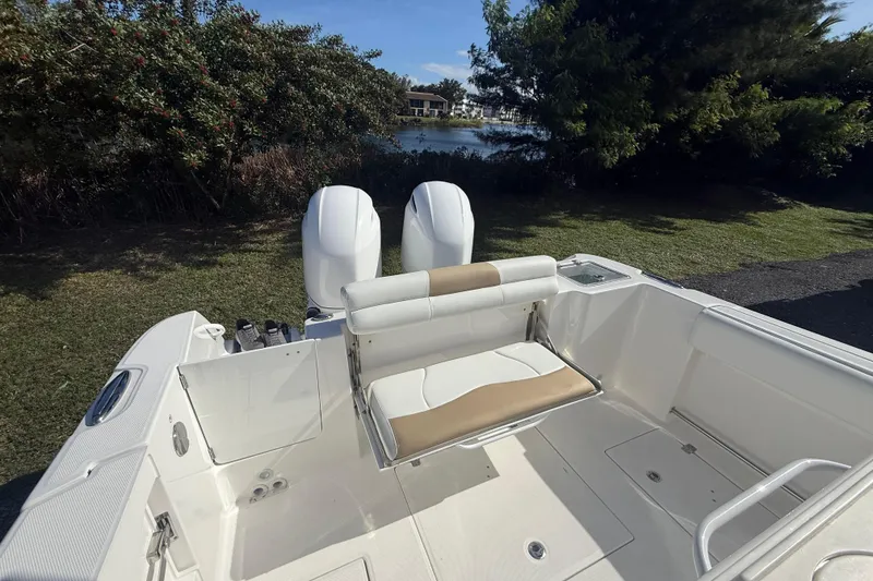 Slide: The Image of 2021 Edgewater 262CC boat with dual engines and seating, near a scenic waterway. - 4