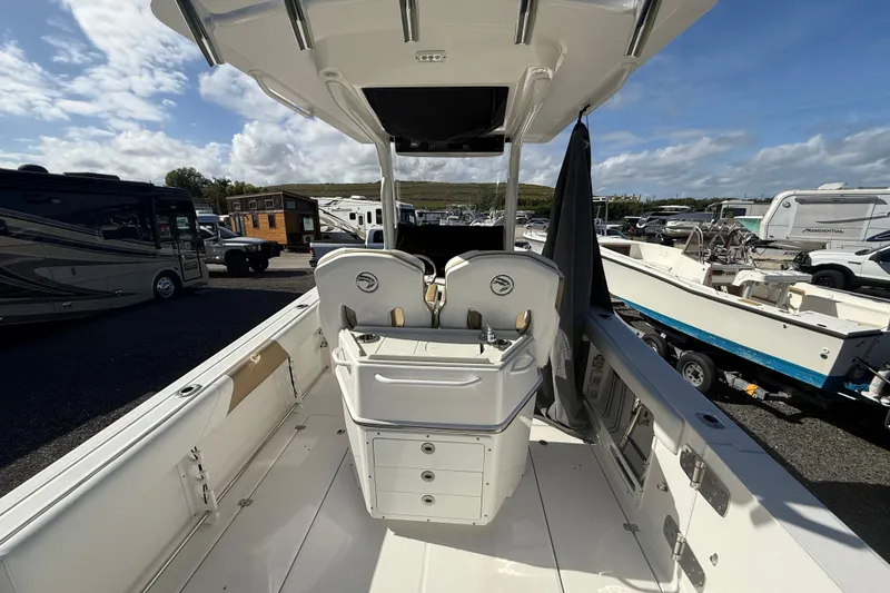 Slide: The Image of 2021 Edgewater 262CC boat interior with seating and storage, parked among RVs and boats. - 5