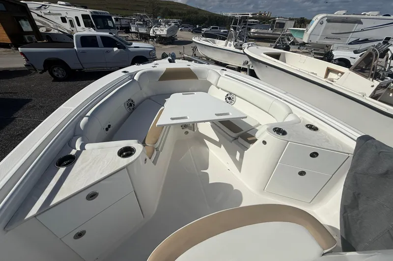 Slide: The Image of 2021 Edgewater 262CC boat interior with seating and table, parked in a marina. - 8