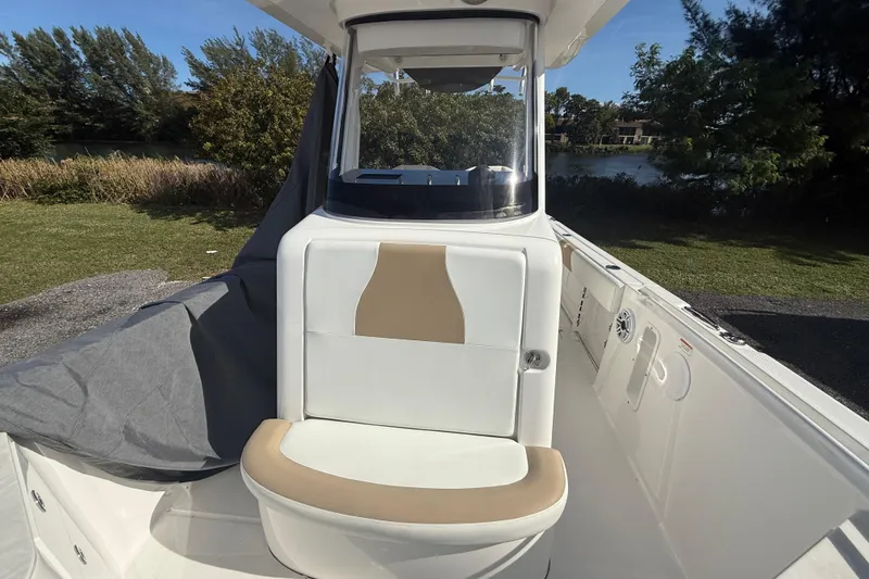 Slide: The Image of 2021 Edgewater 262CC boat interior with cushioned seating and console, set outdoors. - 9
