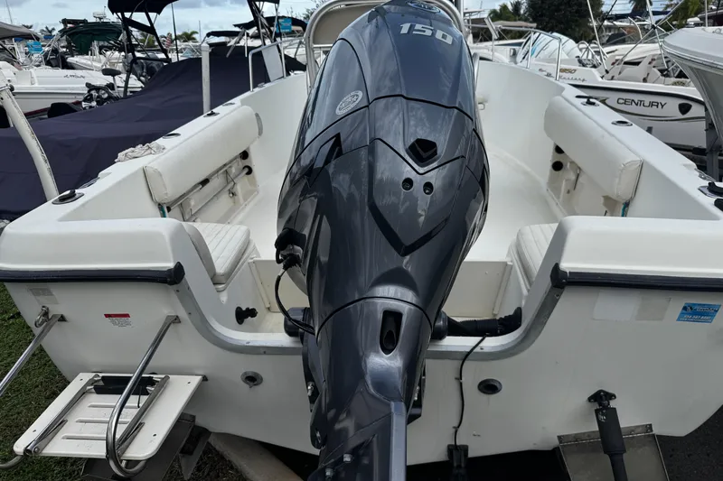 Slide: The Image of 2023 Hydra-Sports 212 CC boat with powerful outboard motor, docked among other vessels. - 21