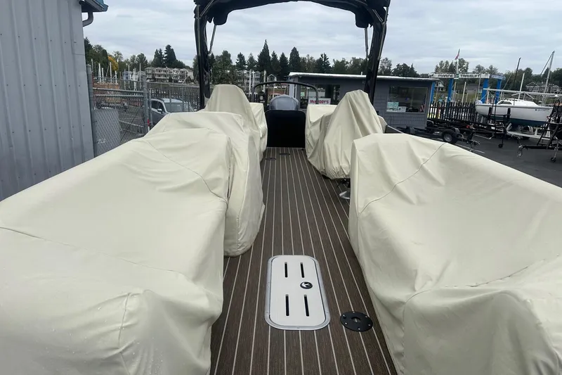 Slide: The Image of 2023 Premier 250 SunSation RF pontoon boat with covered seating, docked at marina. - 8
