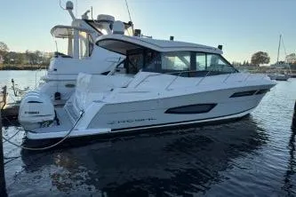 Slide: The Image of 2021 Regal 38 XO boat with triple outboard engines docked at a marina. - 14