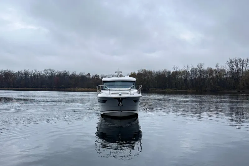 Slide: The Image of 2021 Regal 38 XO yacht on a calm lake under cloudy skies. - 7